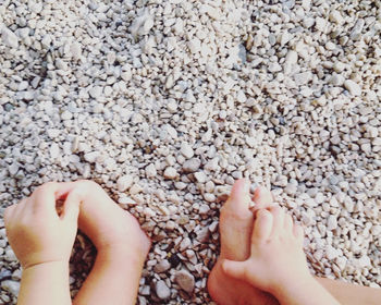 Cropped image of baby sitting on stone covered field