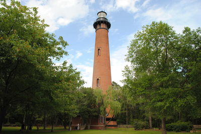 Low angle view of trees and tower against sky