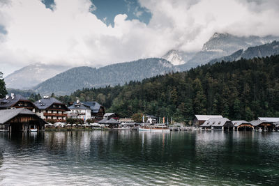 Houses by river and buildings against sky