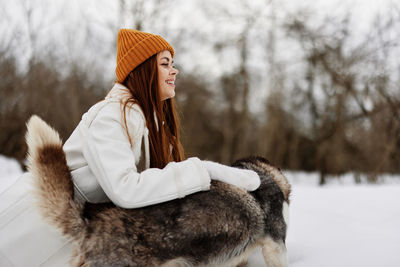 Portrait of woman with dog on snow covered field