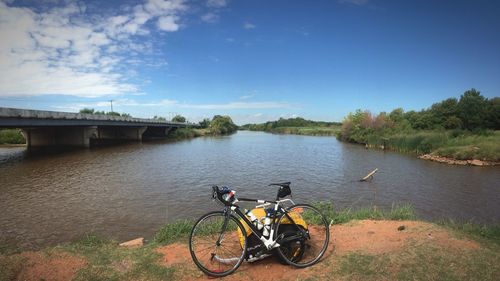 Bicycle on bridge over river against sky