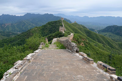 High angle view of great wall of china by mountains against cloudy sky