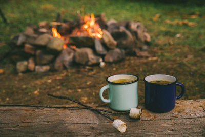 Two metal cups with tea and marshmallows. fire on background. union with nature