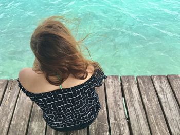 High angle view of woman sitting on plank by sea 