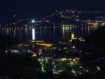 High angle view of illuminated buildings by river at night