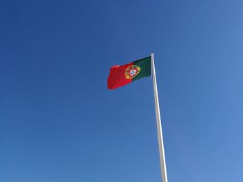 Low angle view of portuguese flag against clear blue sky