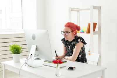 Young woman using phone while sitting on table