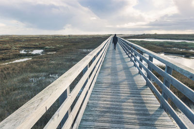 Rear view of boy walking on footbridge