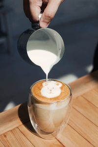 Cropped hand pouring coffee on table