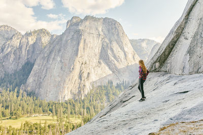 Young woman standing on el capitan mountain looking out to yosemite