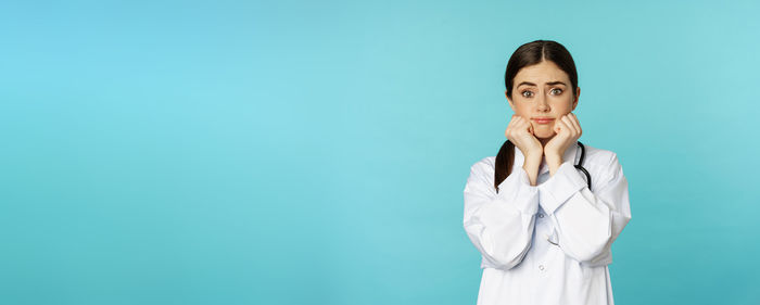 Businesswoman talking on phone while standing against blue background