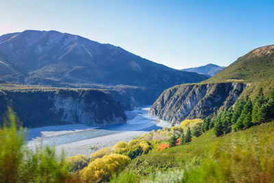 Scenic view of river amidst mountains against clear sky
