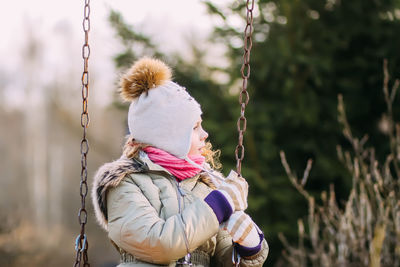 Smiling girl sitting on swing at park