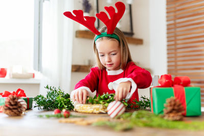 Portrait of cute girl playing with christmas tree at home