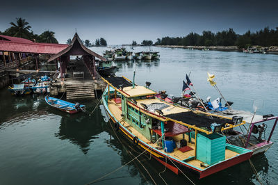 Fishing boats moored in river against sky