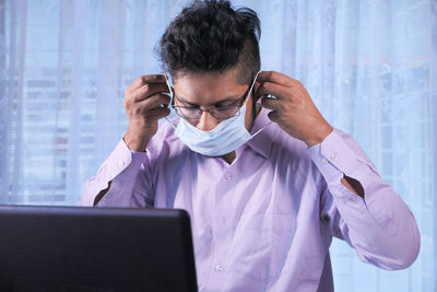 Close-up of man wearing mask sitting at office