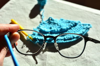 Close-up of hand holding eyeglasses on table