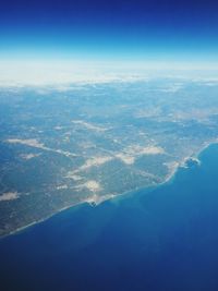 Aerial view of sea and cityscape against blue sky