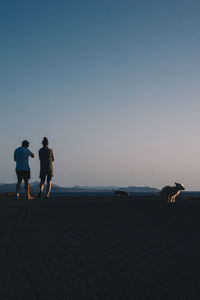 Rear view of woman walking on beach against clear sky