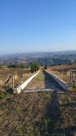 Road amidst field against clear sky