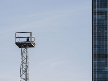 Low angle view of lookout tower and modern skyscraper against sky