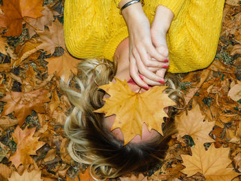 Low section of woman with yellow leaves during autumn