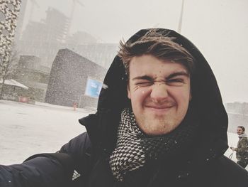 Portrait of smiling man standing in city during snowfall