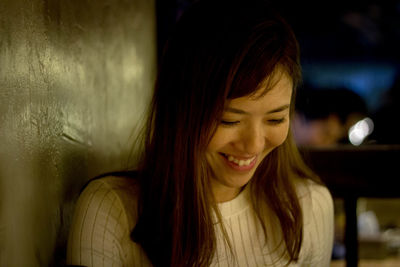 Close-up of happy beautiful woman by wall at night