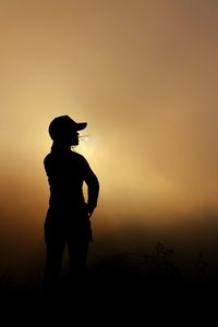 Silhouette man standing on field against sky during sunset