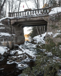 Snow covered bridge against trees during winter