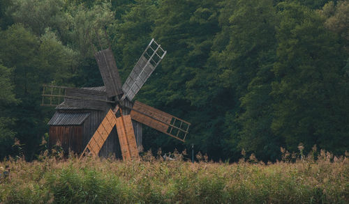 Traditional windmill on field against trees