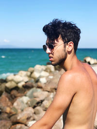 Young man looking at sea shore against sky