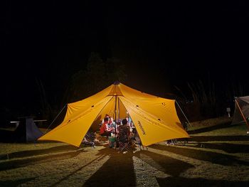 Rear view of people at tent against sky at night