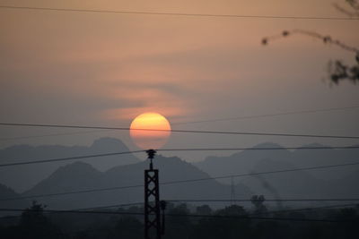 Silhouette electricity pylon against sky during sunset