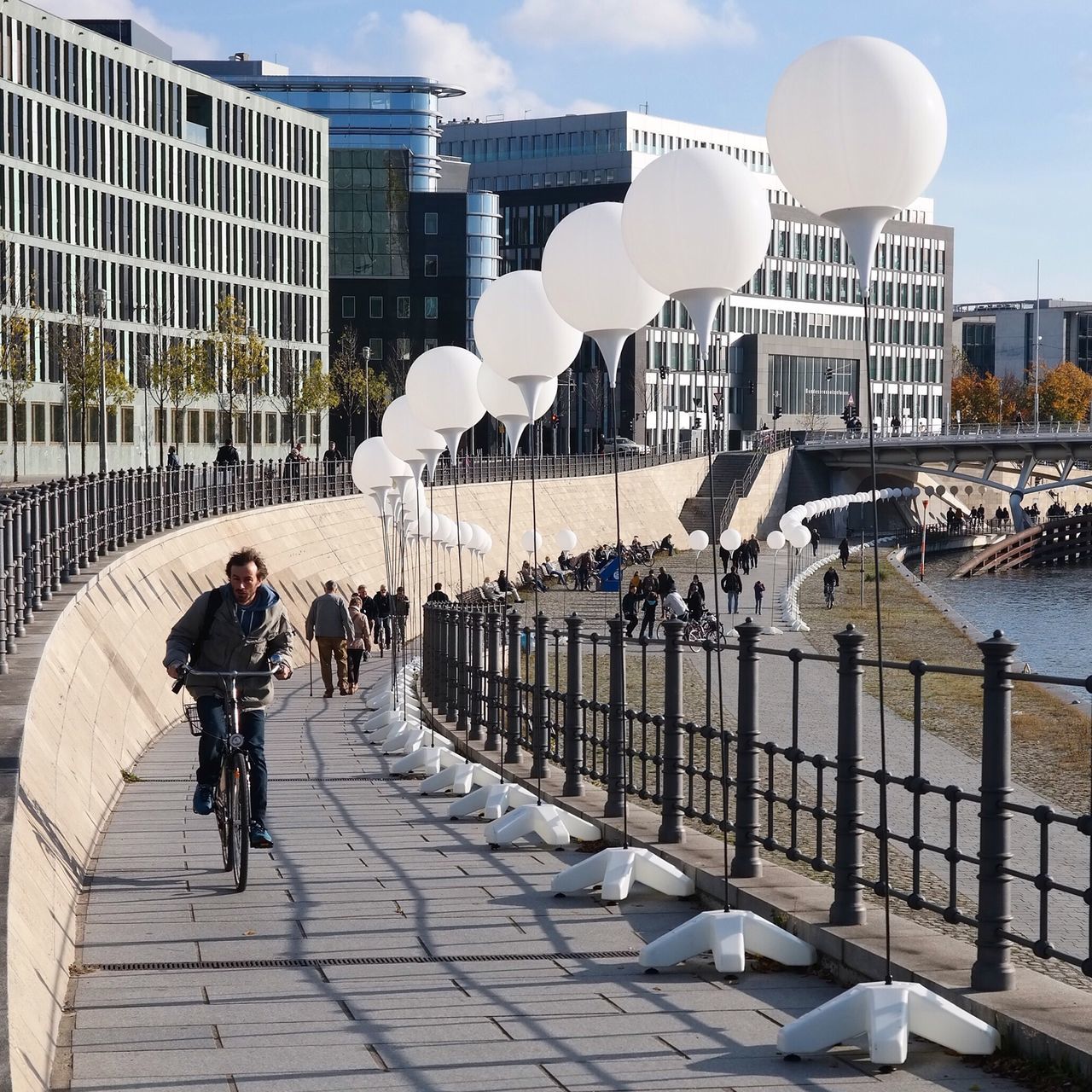 architecture, building exterior, built structure, city, lifestyles, full length, leisure activity, men, walking, sky, city life, person, water, casual clothing, rear view, railing, building