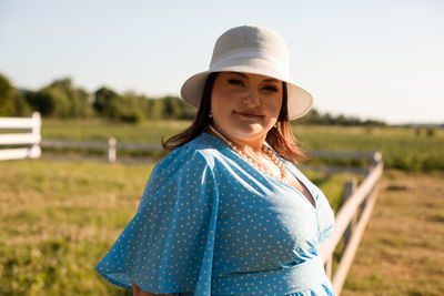 Portrait of young woman wearing hat standing on field