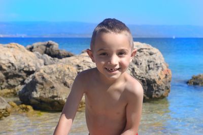 Portrait of happy boy on rock at sea shore