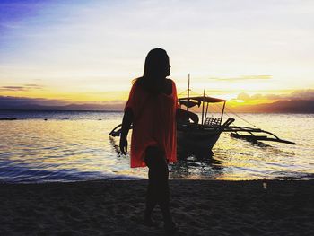 Rear view of silhouette woman walking on beach