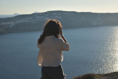 Side view of young woman standing against sea