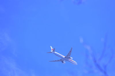 Low angle view of airplane against clear blue sky
