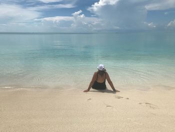 Rear view of woman at beach against sky