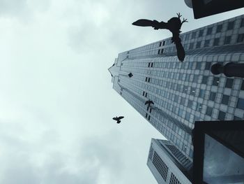 Low angle view of man jumping in city against sky
