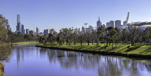 Scenic view of river by buildings against clear sky