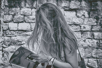 Rear view of woman sitting against wall