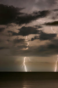 Lightning over illuminated landscape against sky at night