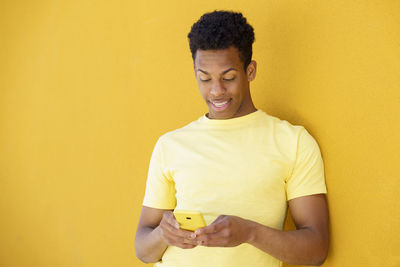 Portrait of a smiling young man against yellow wall
