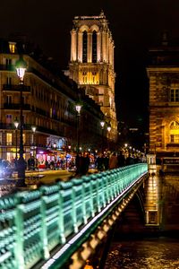 Illuminated bridge over canal in city at night