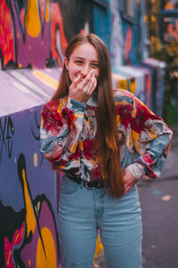 Portrait of smiling young woman standing on street in city