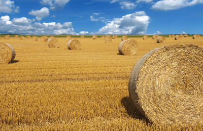 Hay bales on field against sky