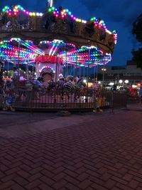 Illuminated carousel in amusement park at night